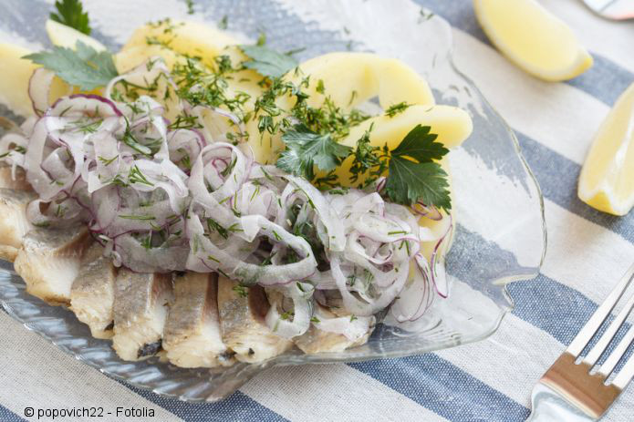 Herring with onion on a plate in the form of fish